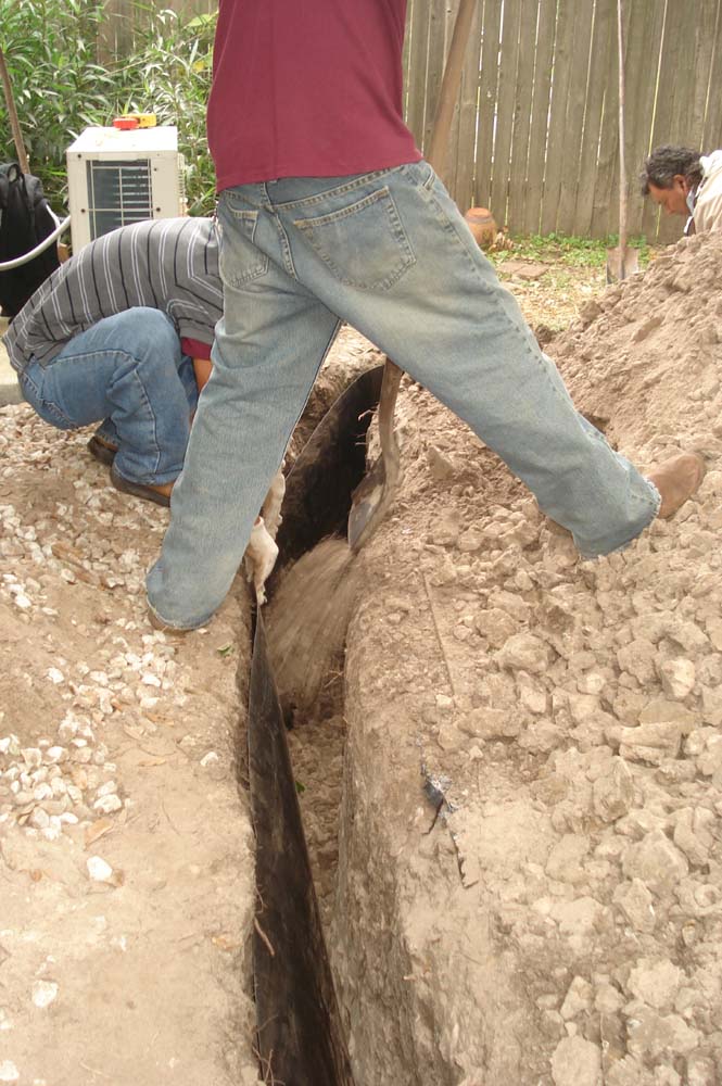 Workers continue to back-fill the trench with dirt - Foundation Repair in Plano, Texas