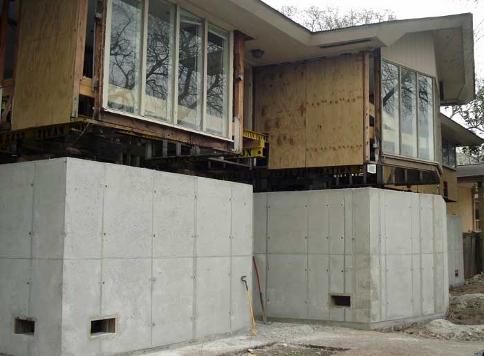 Concrete walls are built to support a house that has been elevated approximately 10 feet.