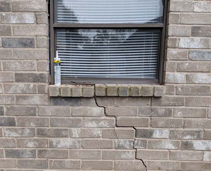 This exterior photo shows the separation of the brick from the window frame and the crack in the brick exterior.
