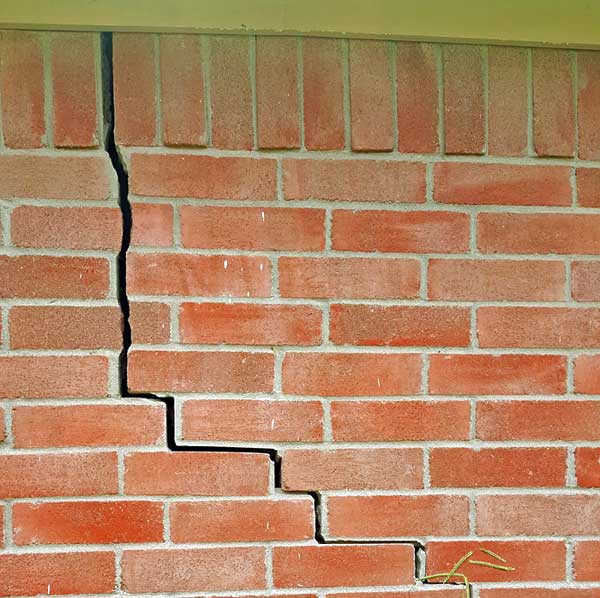 Soil movement has cracked the home's slab foundation and resulted in additional damage to the home's exterior brick wall.